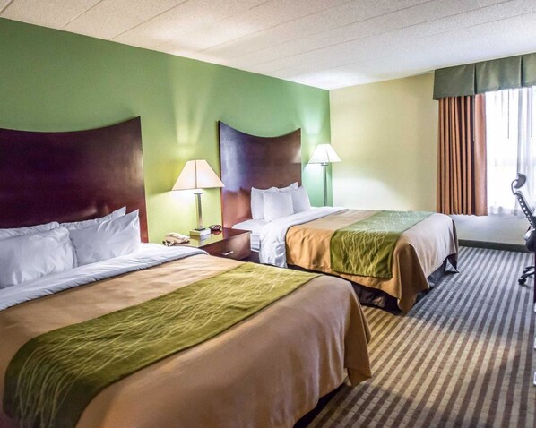 A hotel room with two beds, green walls, and a striped carpet.