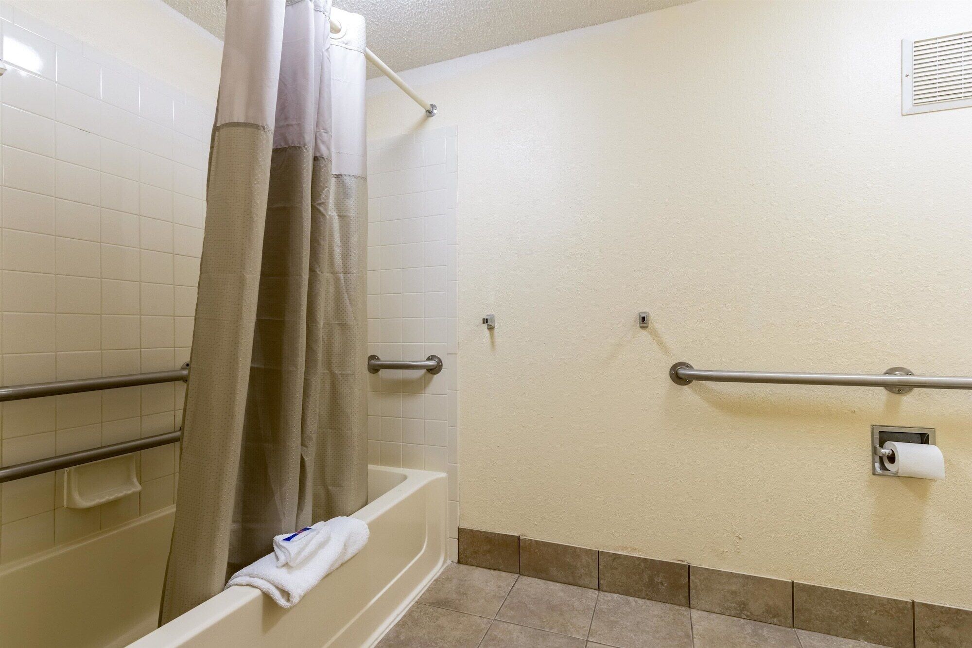 Une salle de bain équipée d’une douche, de barres d’appui et d’un porte-serviettes.