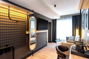 Una camera d'albergo moderna con divano, tavolino, televisione e specchio.