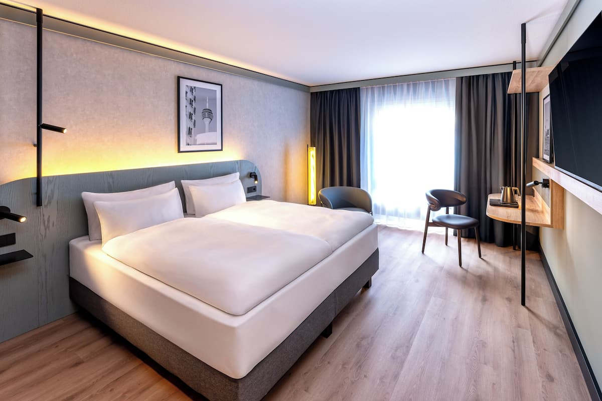 Een moderne hotelkamer met een groot bed, een bureau en een stoel.