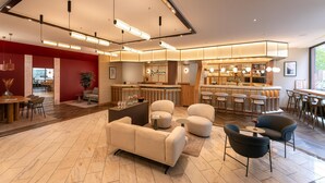 A modern hotel lobby with a bar area, seating arrangements, and a reception desk.