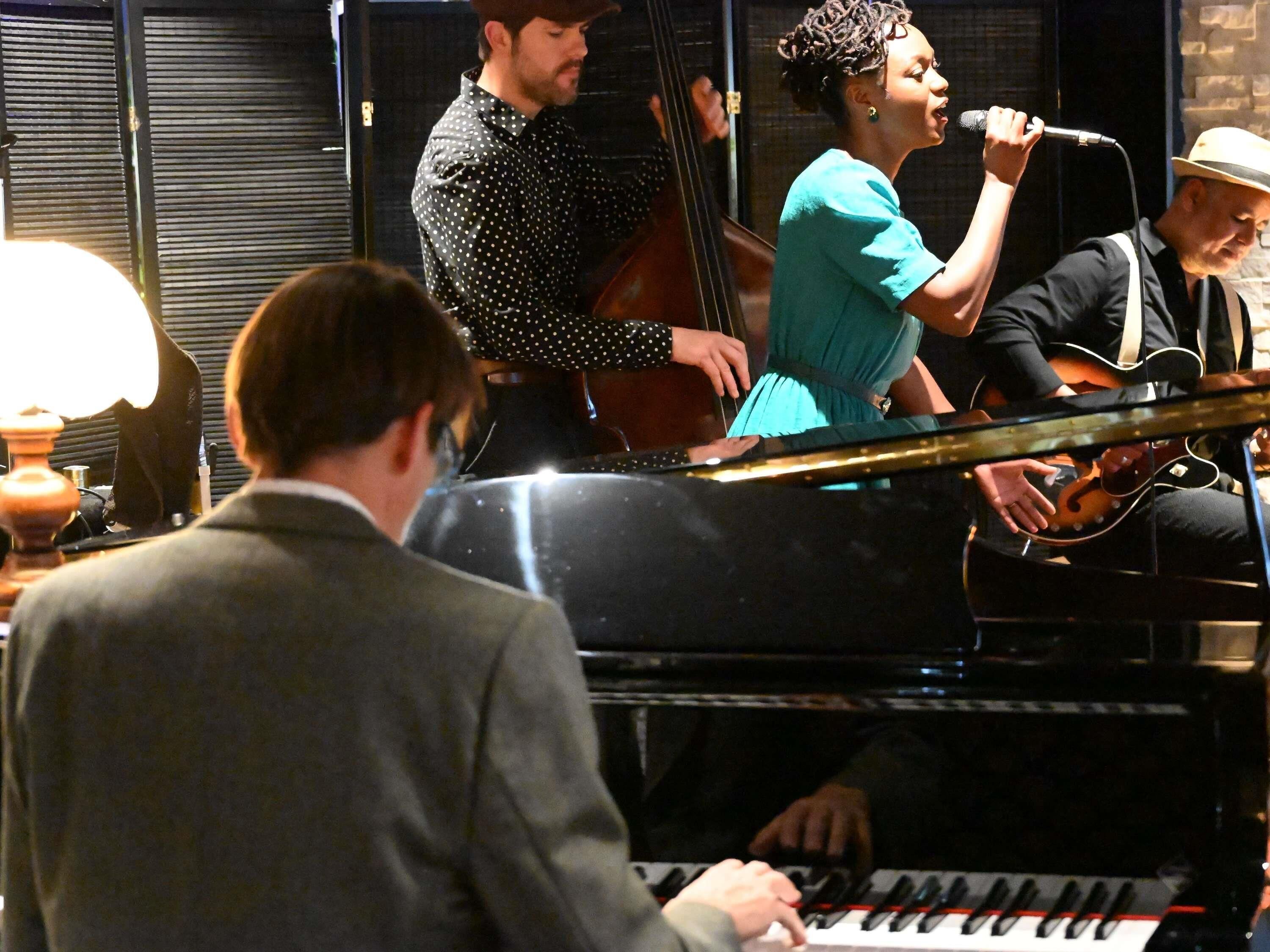 A group of musicians performing with a piano and guitar.