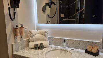 A modern bathroom with a large mirror, a sink, and a towel rack.
