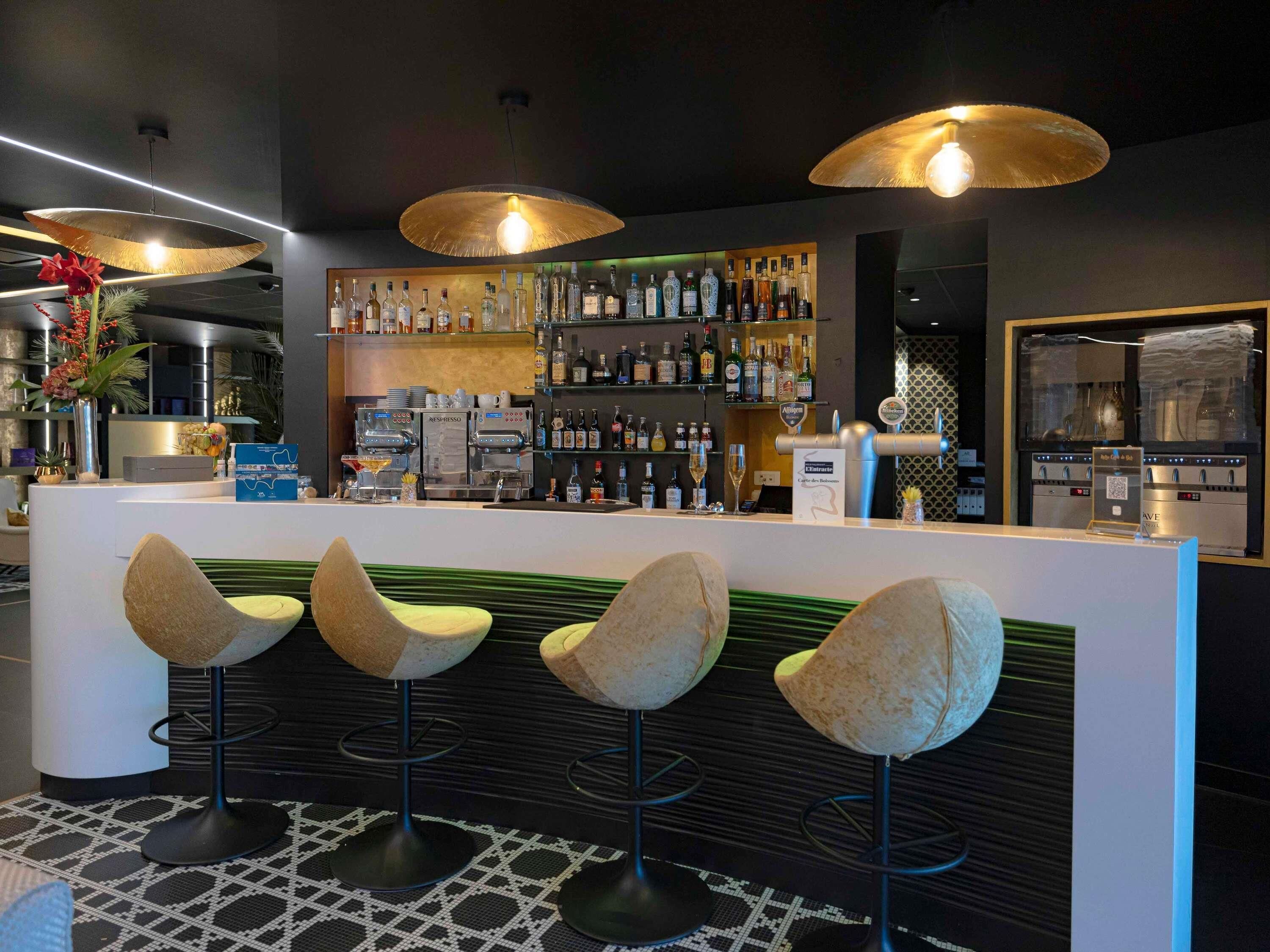 A bar area with a counter, bar stools, and a variety of bottles and glasses.