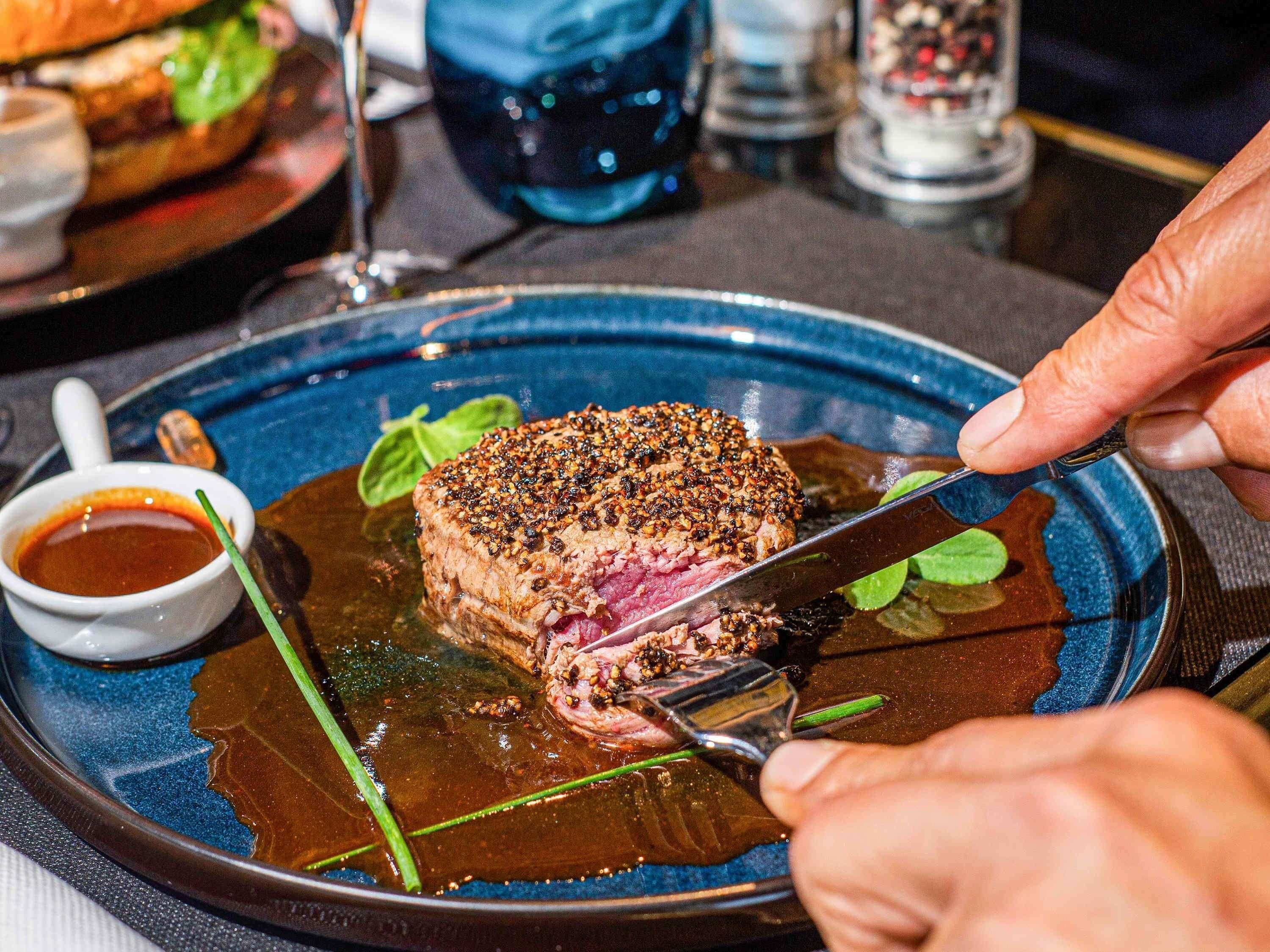 A steak with a dark sauce on a blue plate.