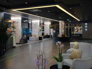 A modern lobby with a reception desk, seating areas, and decorative plants.