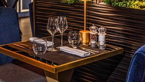 Una mesa de comedor con copas de vino, una vela, saleros y pimenteros, y una servilleta.