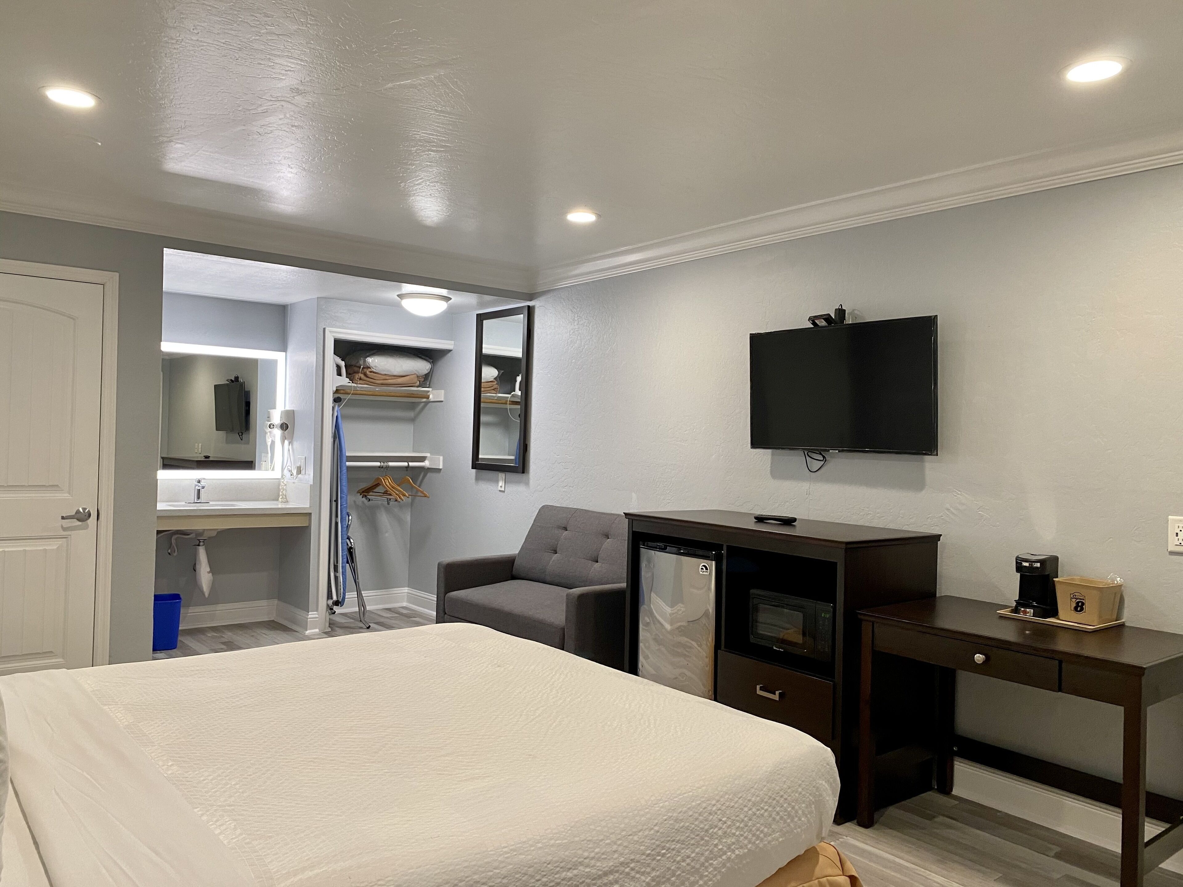 A bedroom with a bed, a desk, a television, and a built-in oven.
