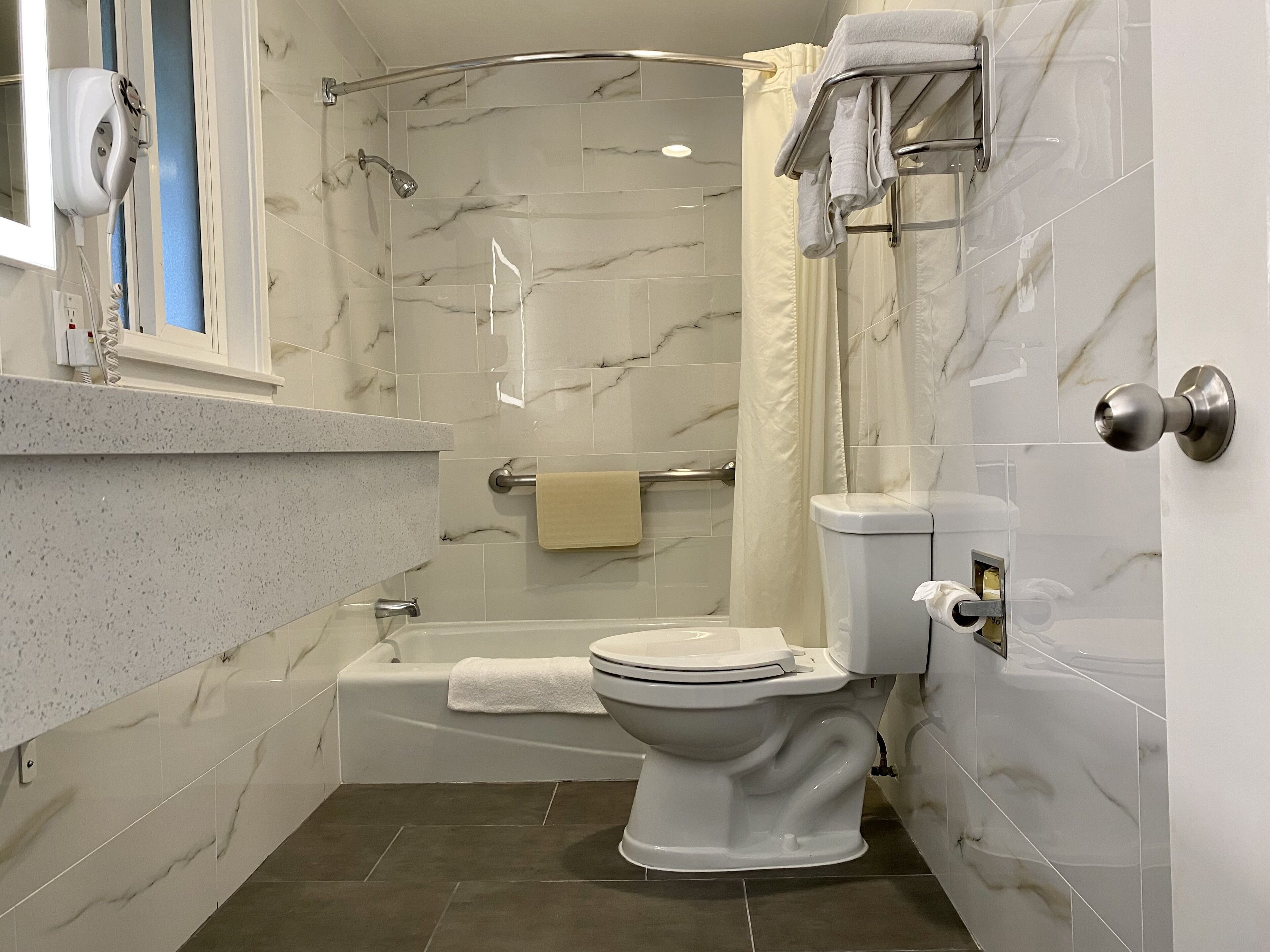 A bathroom with a toilet, bathtub, and shower.