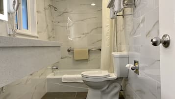 A bathroom with a toilet, bathtub, and shower.