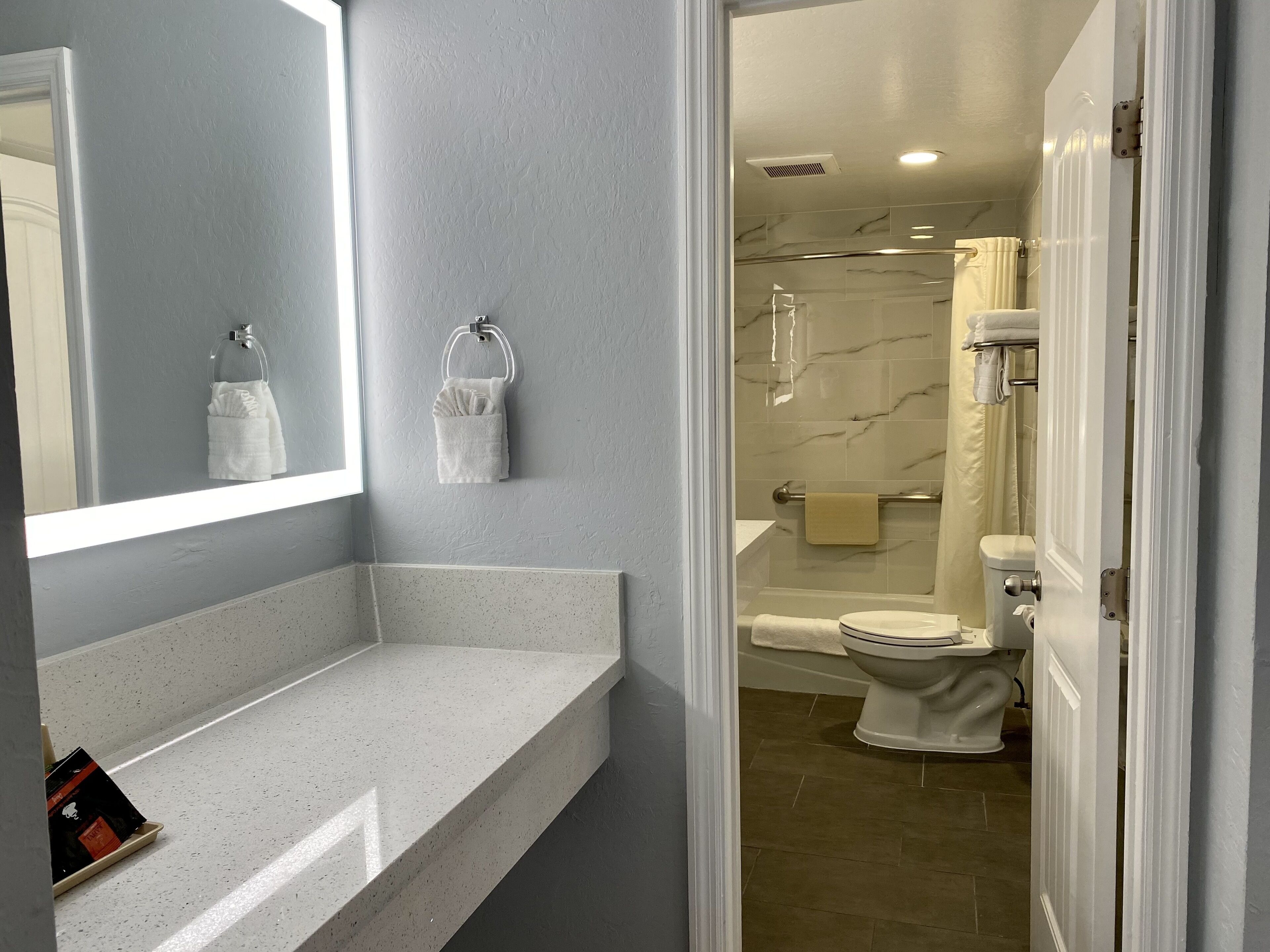 A bathroom with a marble shower, a toilet, and a sink with a towel rack.