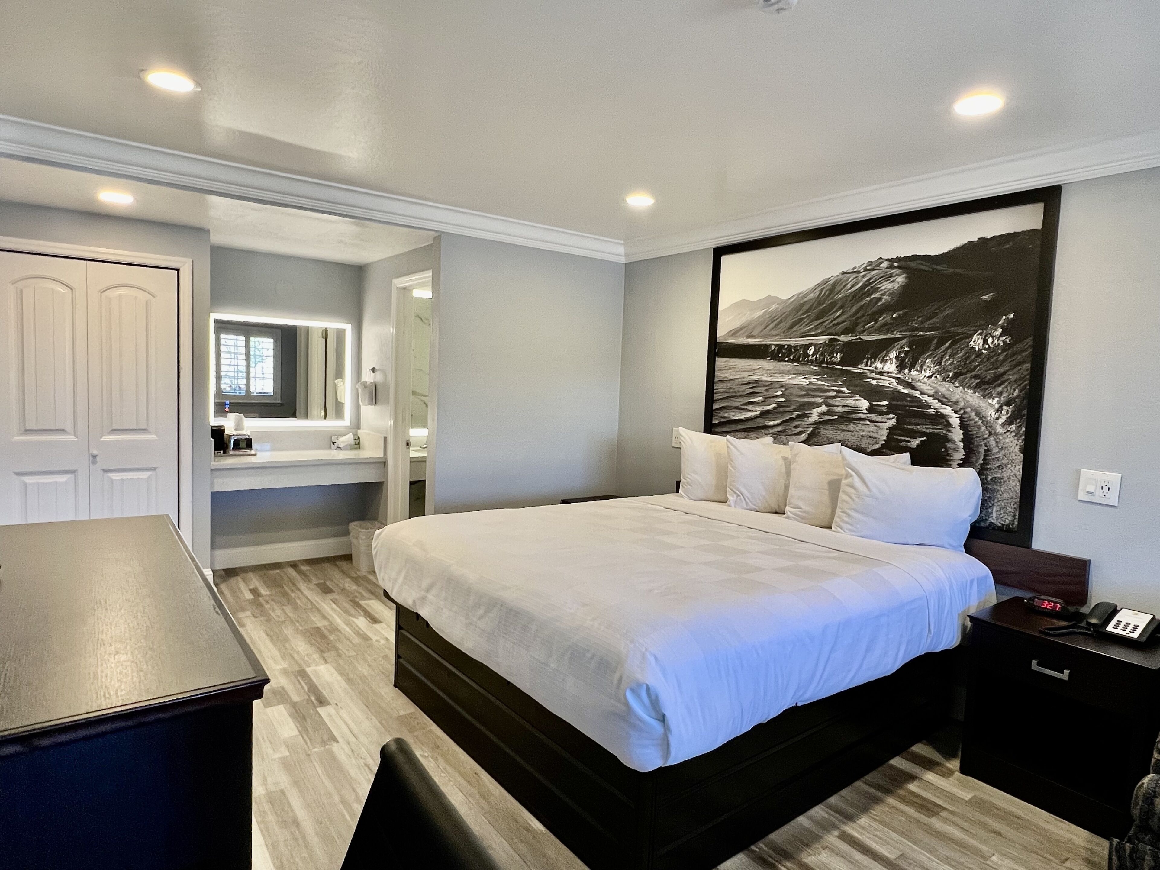 A bedroom with a bed, bedside table, and a large framed picture on the wall.