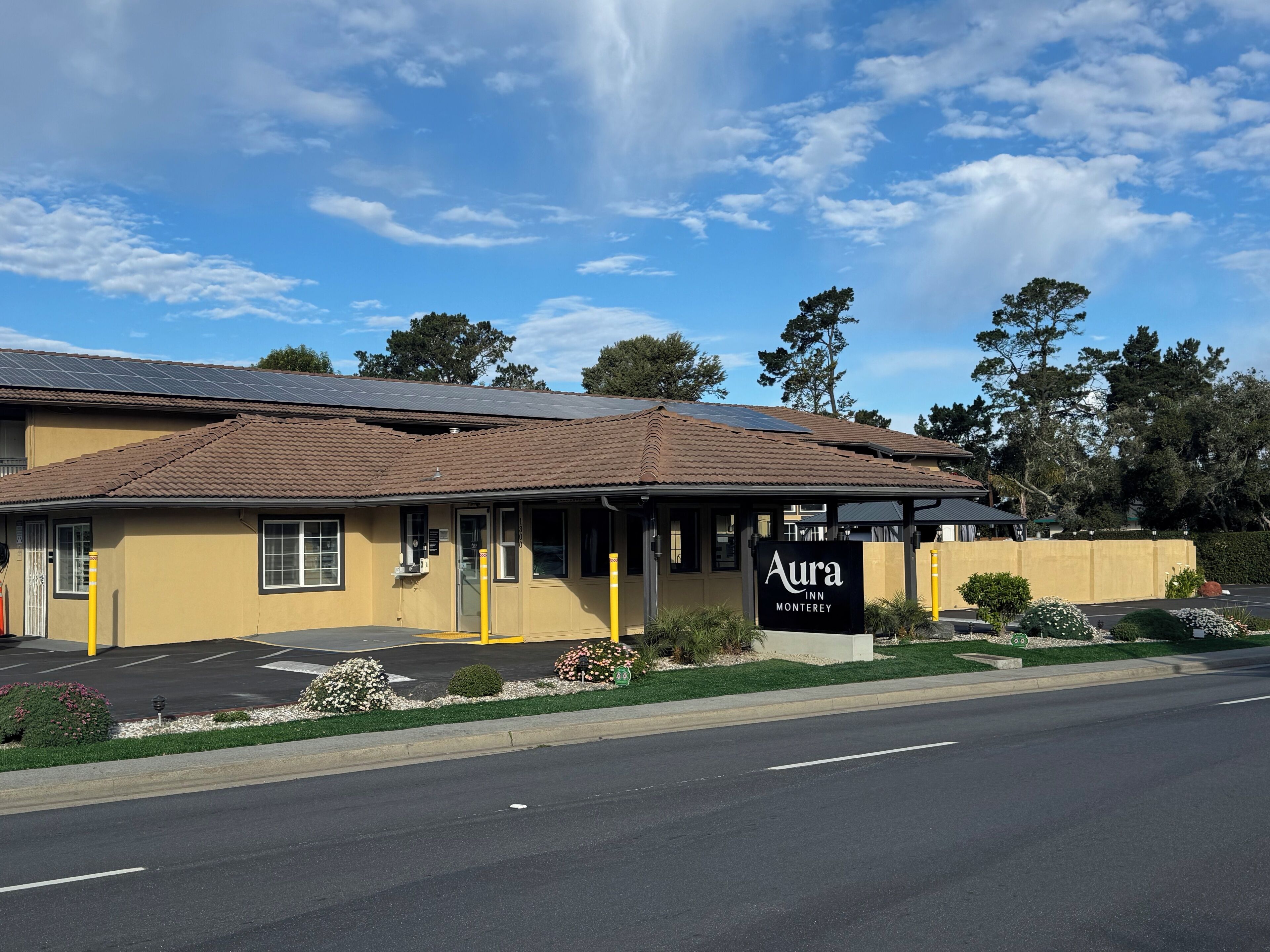 A motel with a sign reading "Aura Inn Monterey" and a parking lot in front.