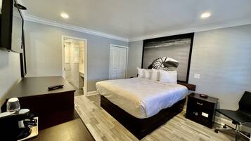 A modern hotel room with a large bed, a desk, a chair, and a flat-screen TV.