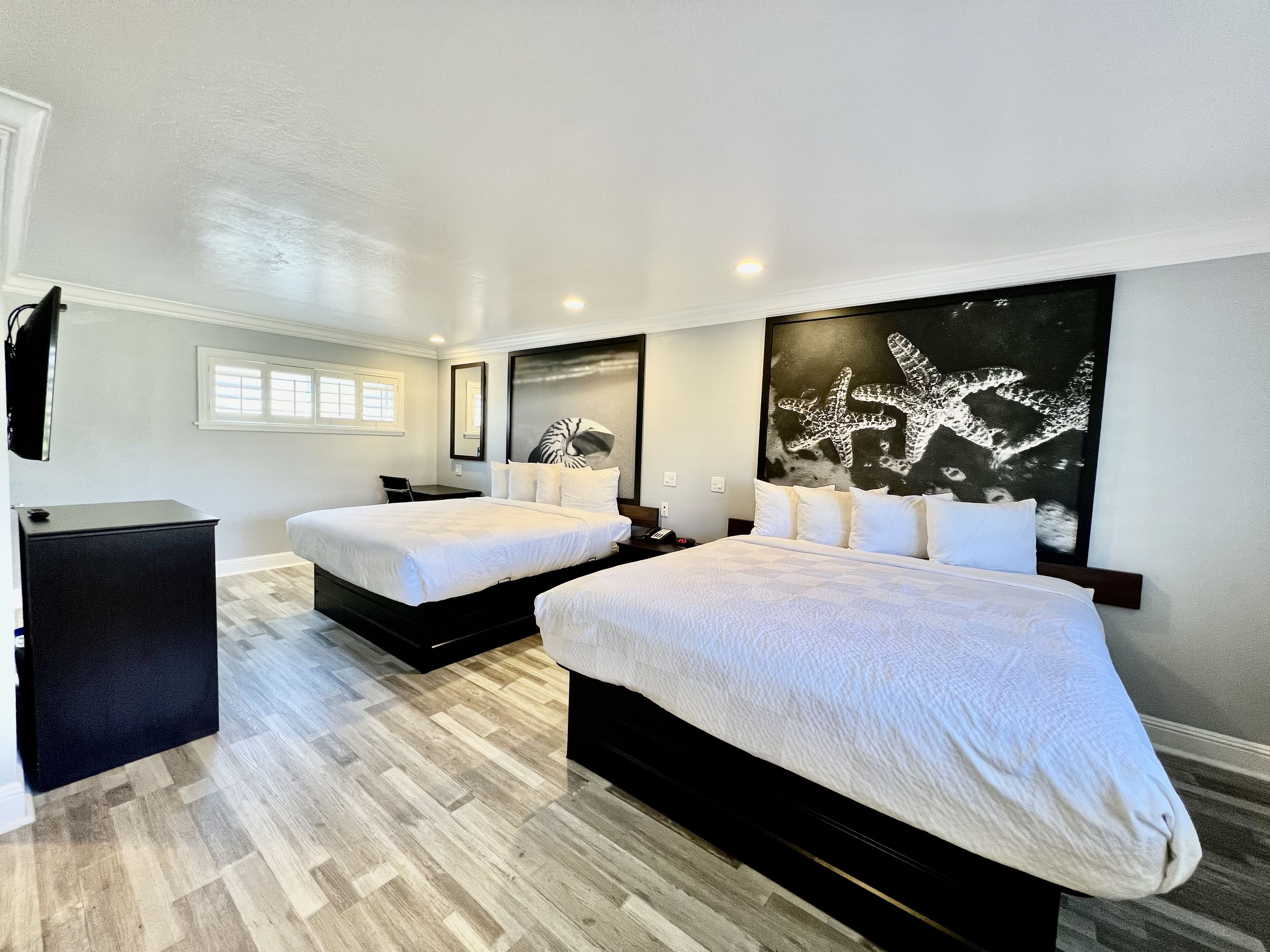 Habitación de hotel con dos camas, un escritorio y una obra de arte grande en la pared.