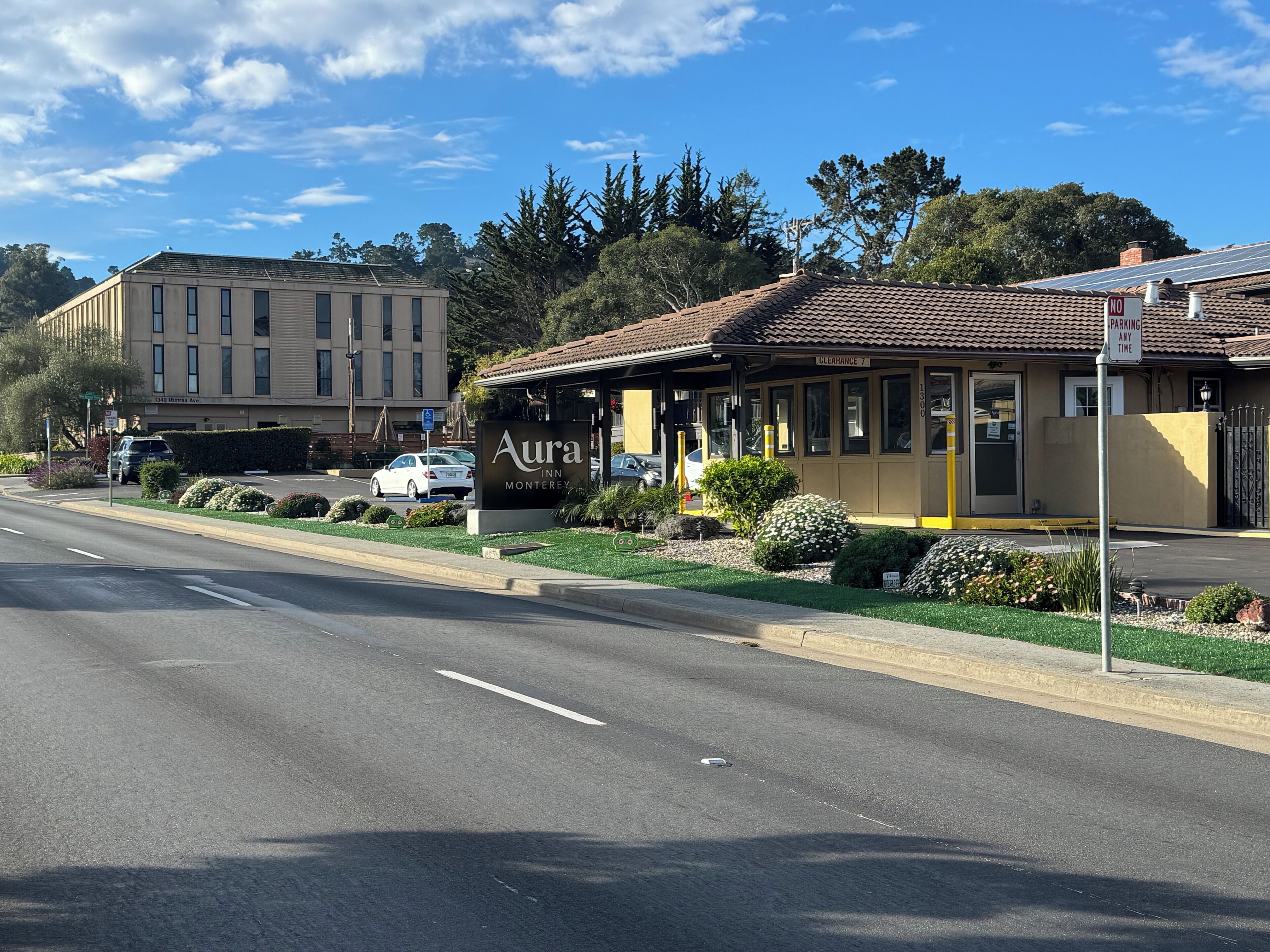 Hotel com entrada acessível, placa de estacionamento e sinalização de área de passagem.