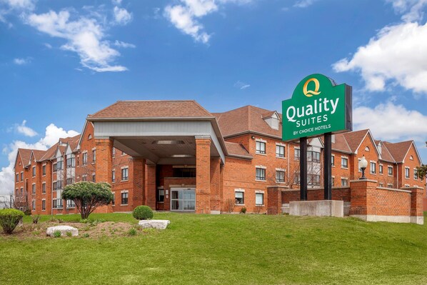 Un edificio de ladrillo con un letrero verde que dice 'Quality Suites by Choice Hotels'.