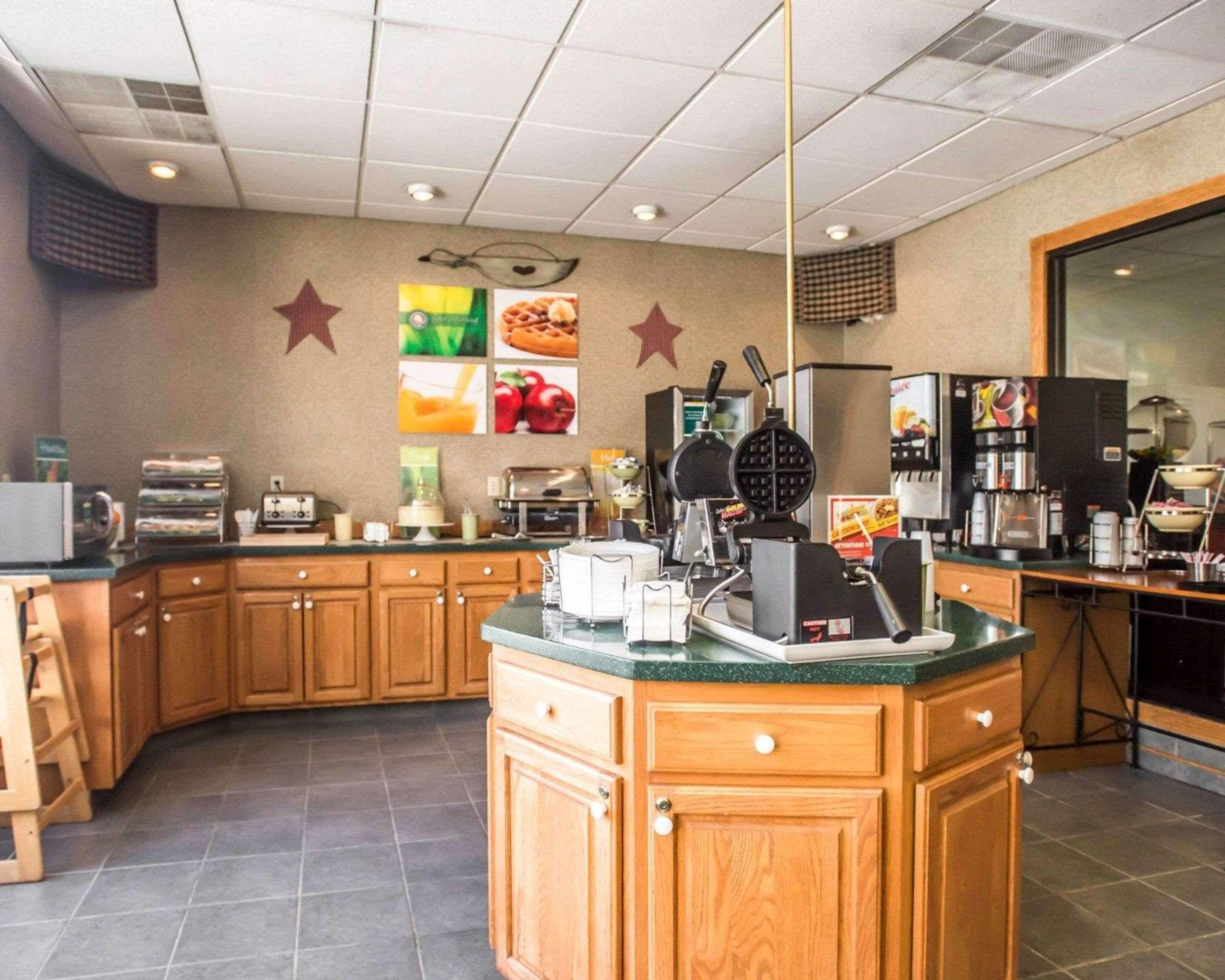 A kitchen with wooden cabinets, a central island, a waffle maker, a coffee machine, and a refrigerator.