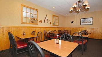 Un ristorante con pareti in legno, diversi tavoli e sedie, un lampadario e decorazioni murali tra cui figure di animali e una stella.