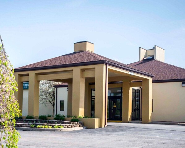 Hotel entrance with a covered area and landscaped garden.