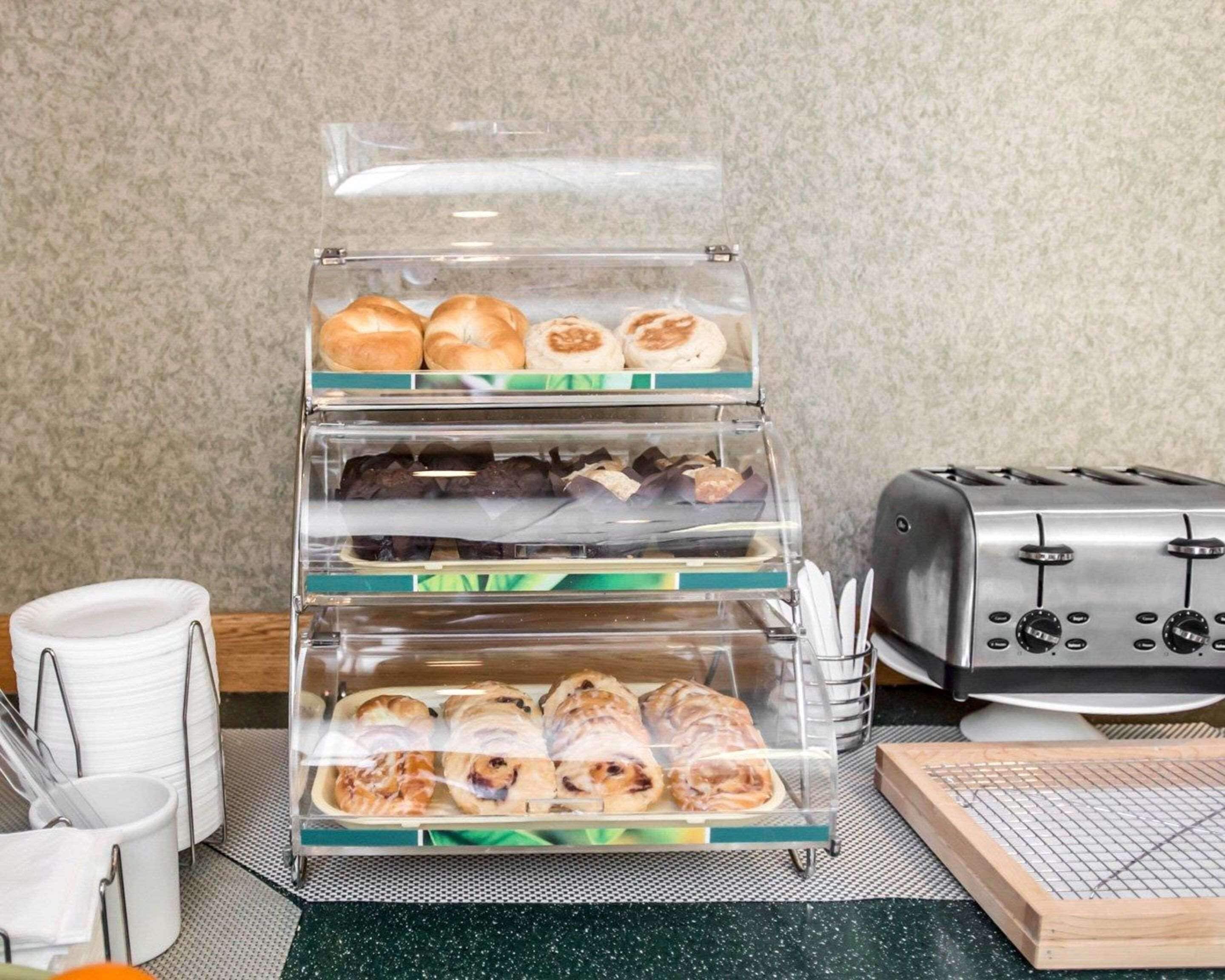 Mostrador de panadería con distintos productos horneados en recipientes transparentes, una tostadora y utensilios de cocina sobre una encimera.