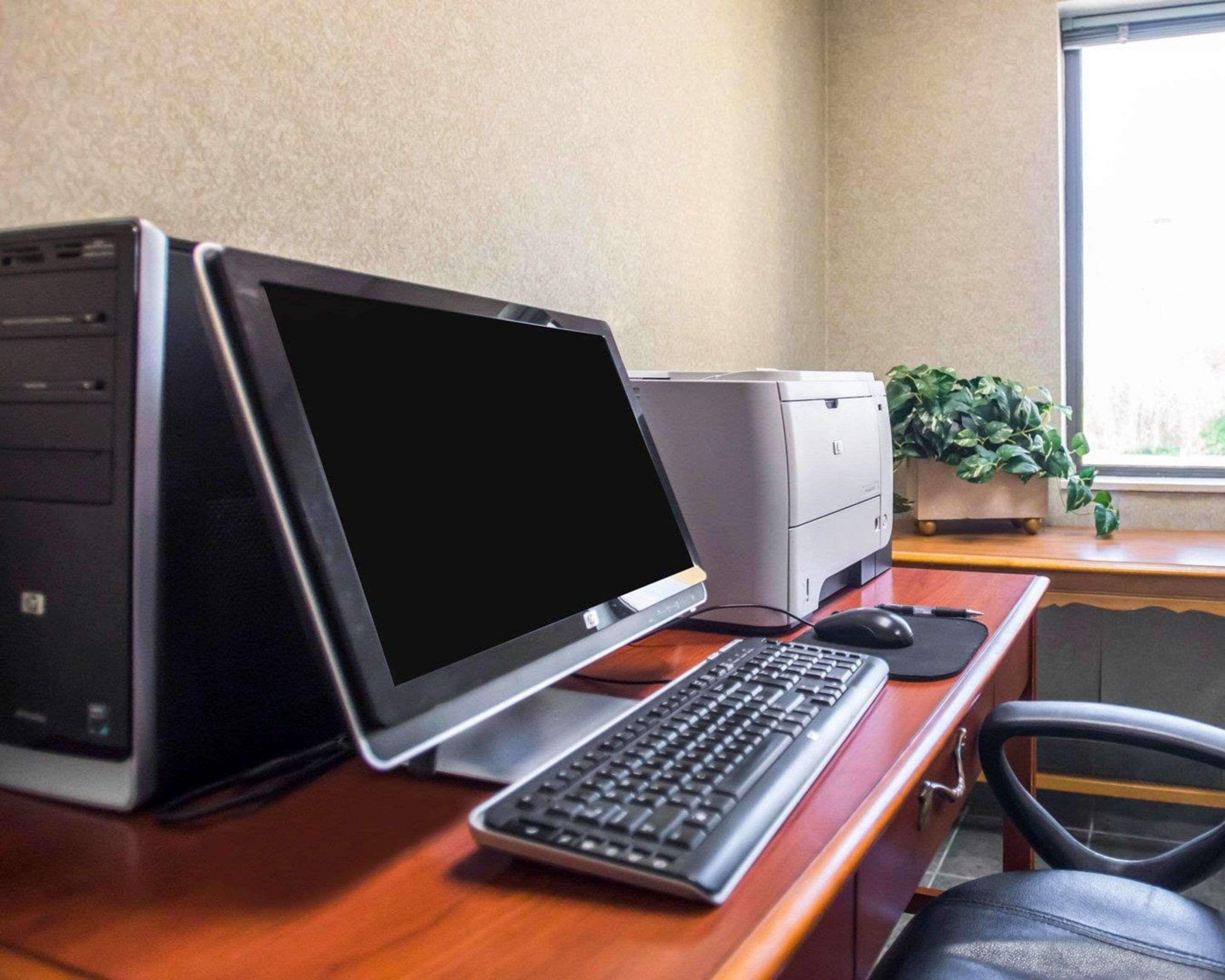 A desk with a laptop, a desktop computer, a printer, and a keyboard.