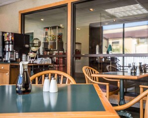 Un restaurante con una mesa, sillas, una máquina de café y un amplio ventanal.
