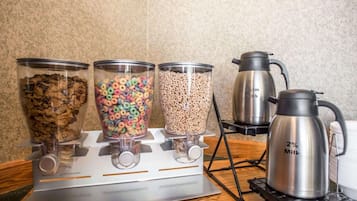 Uma cozinha com três recipientes de vidro em uma fogão, um caldeirão de leite e uma cafeteira.