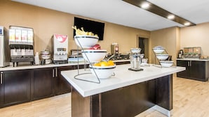 A buffet area with a coffee station, fruit bowls, and a beverage dispenser.