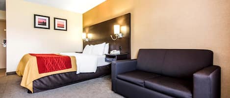 Une chambre d’hôtel comprenant un lit, un canapé, une table de chevet et deux lampes fixées au mur.