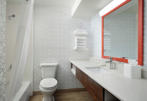 A bathroom with a toilet, a sink, a mirror, and a shower curtain.