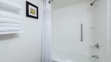 A bathroom with a white bathtub, a shower with a glass door, and a towel rack with folded towels.