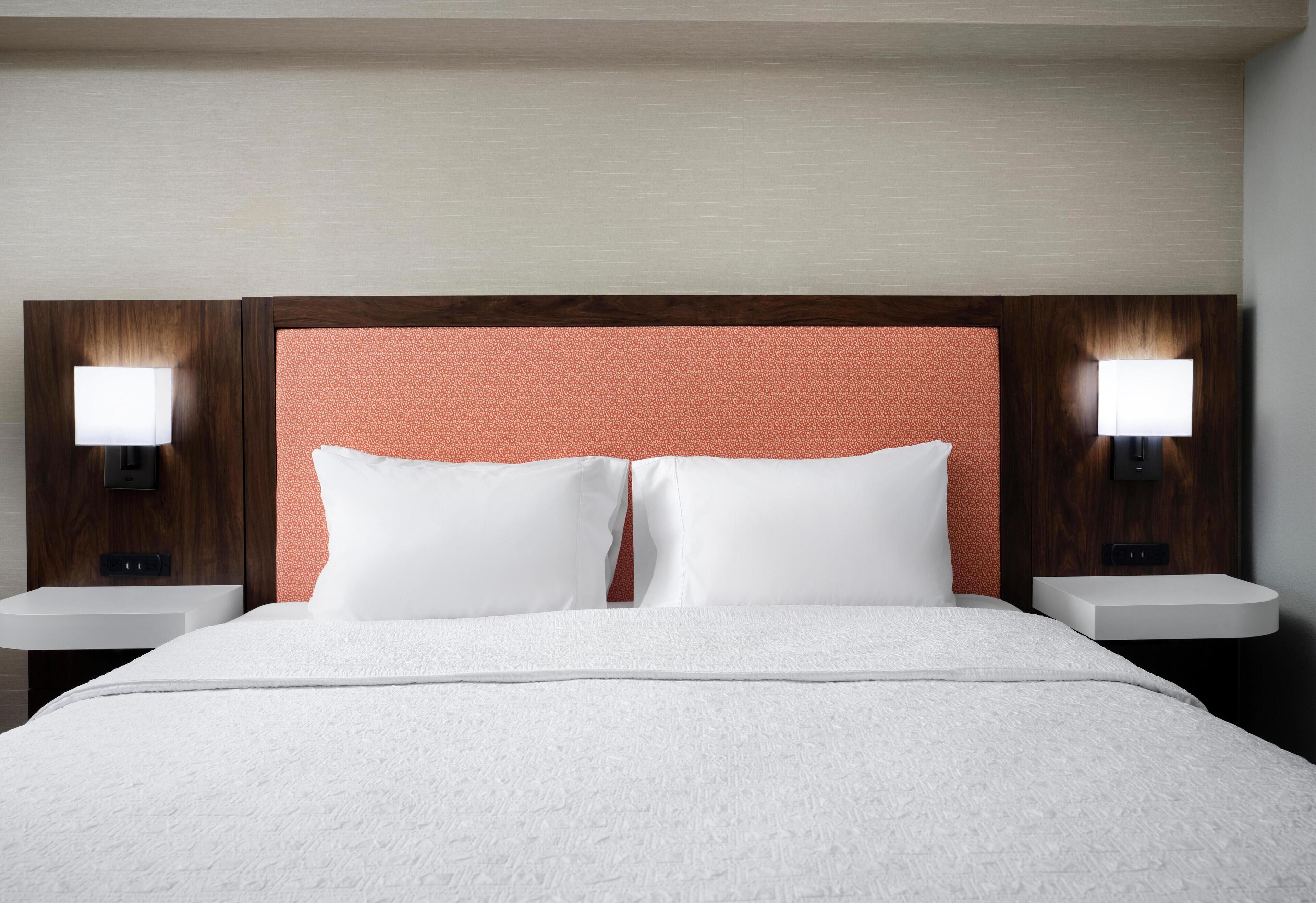 Habitació d'hotel amb un llit gran, dues taules de nit i un capçal de llit amb un disseny texturat.