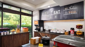 A breakfast bar with a chalkboard menu, a coffee machine, and various food containers.