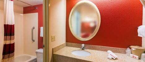 A bathroom with a shower, toilet, sink, and a mirror.