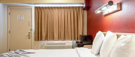 Habitación de hotel con cama, televisión, calentador y una puerta con un letrero.