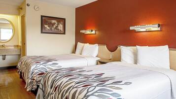 A hotel room with two beds, a bathroom with a round mirror, and a wall-mounted light fixture.