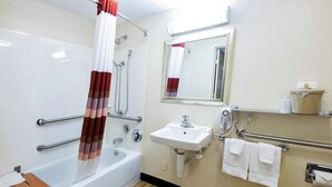 A bathroom with a bathtub, a sink, a mirror, and a hand dryer. - Red Roof Inn St Clairsville - Wheeling West (St. Clairsville)
