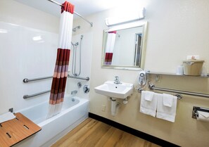 A bathroom with a bathtub, a sink, a mirror, and a hand dryer. - Red Roof Inn St Clairsville - Wheeling West (St. Clairsville)