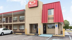 A two-story EconoLodge building with a red and beige facade, a parking lot with marked handicapped spaces, and a white car parked in front. - Econo Lodge Virginia Beach Town Center (Virginia Beach)