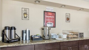 A breakfast bar with coffee makers, cups, and a sign for breakfast hours. - Econo Lodge Virginia Beach Town Center (Virginia Beach)