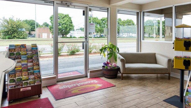 A hotel lobby with a reception desk, a plant, a couch, and a travel information kiosk. - Econo Lodge Virginia Beach Town Center (Virginia Beach)
