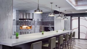 Une cuisine moderne dotée d’un grand îlot central, de tabourets de bar, de luminaires suspendus et d’un four encastré.