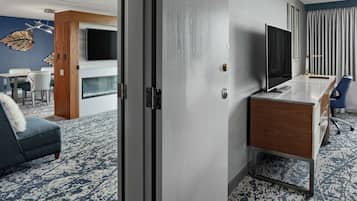 Habitación de hotel con escritorio de madera, televisor de pantalla plana, sofá y chimenea.