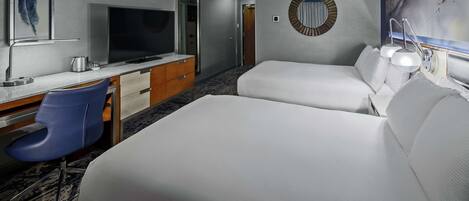 A hotel room with two beds, a desk with a TV, a chair, and a painting on the wall.