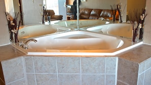 A large, freestanding bathtub with a glass enclosure, a mirror above it, and a tiled floor.