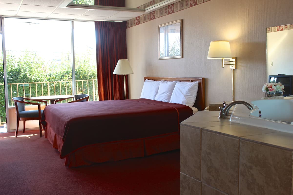 Habitación de hotel con cama, escritorio, silla, baño y vistas al exterior.