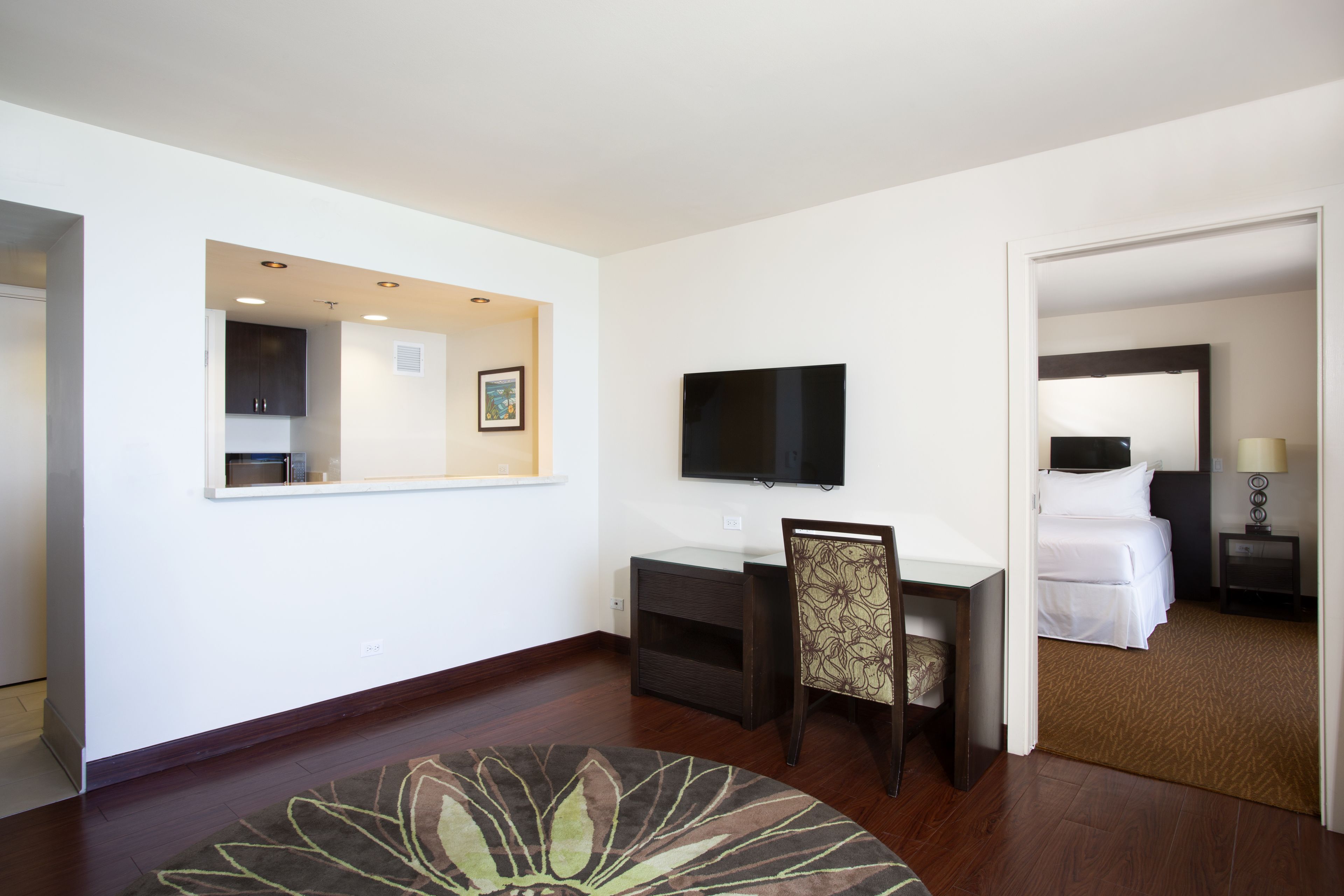 Habitación de hotel con escritorio, silla, televisor de pantalla plana, cama y espejo.