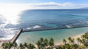 Une plage avec une eau turquoise et limpide, une jetée et des palmiers.