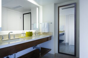 A modern bathroom with a large mirror, two sinks, and a towel rack.